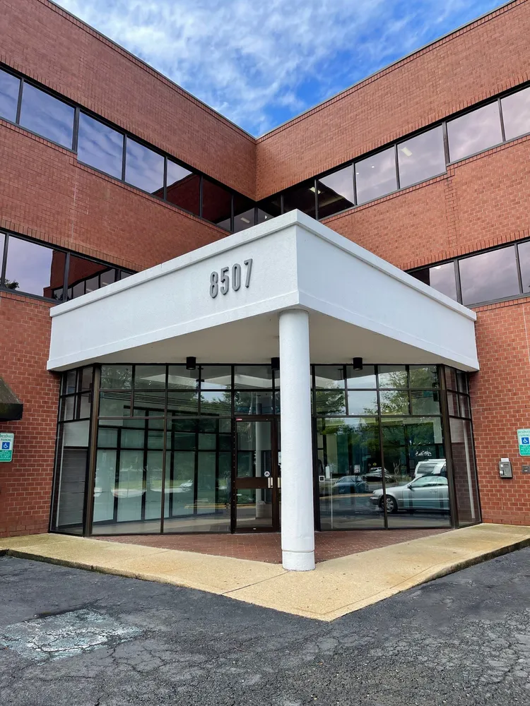 Modern office building entrance with glass doors and brick facade.