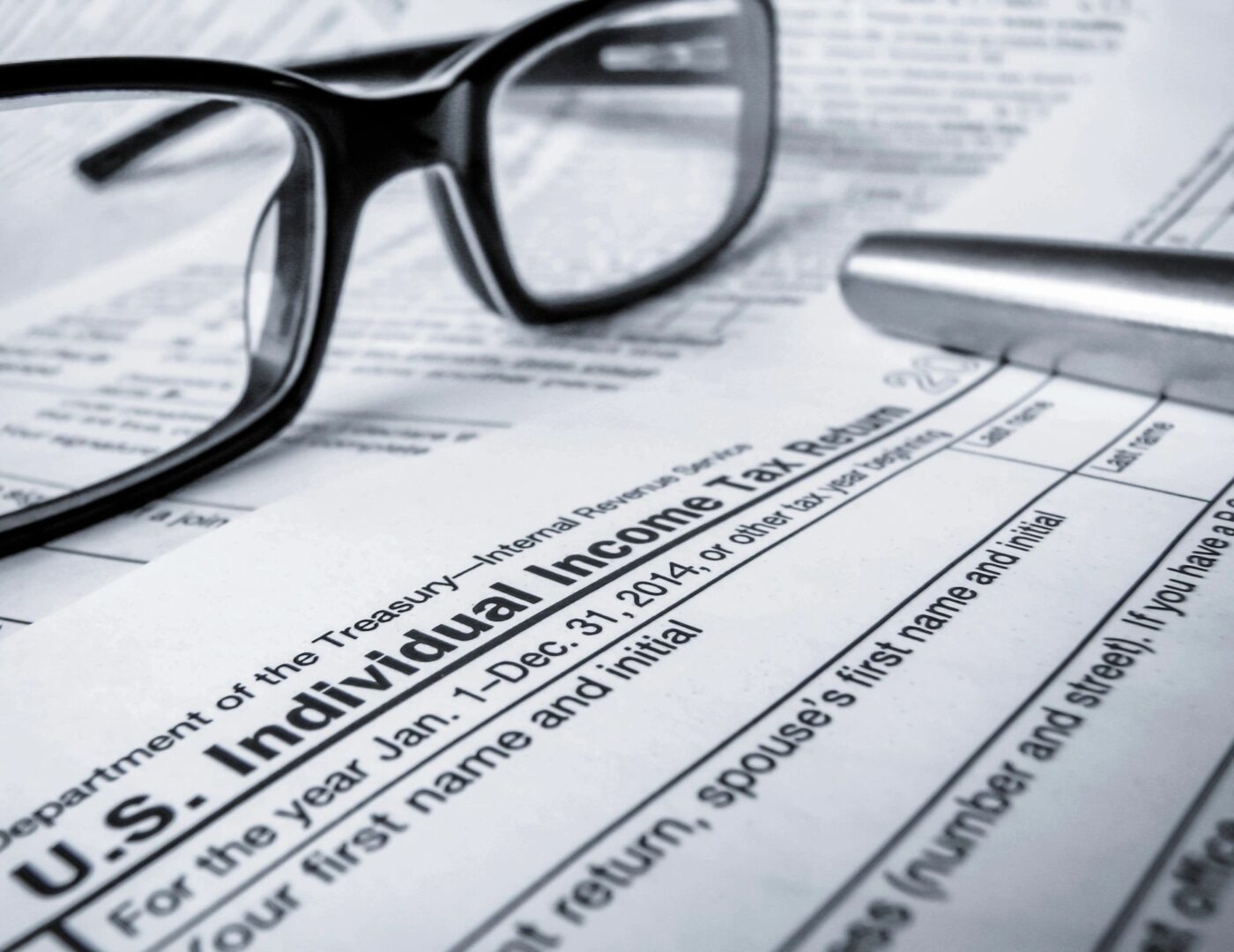 Close-up of tax form with glasses and pen.
