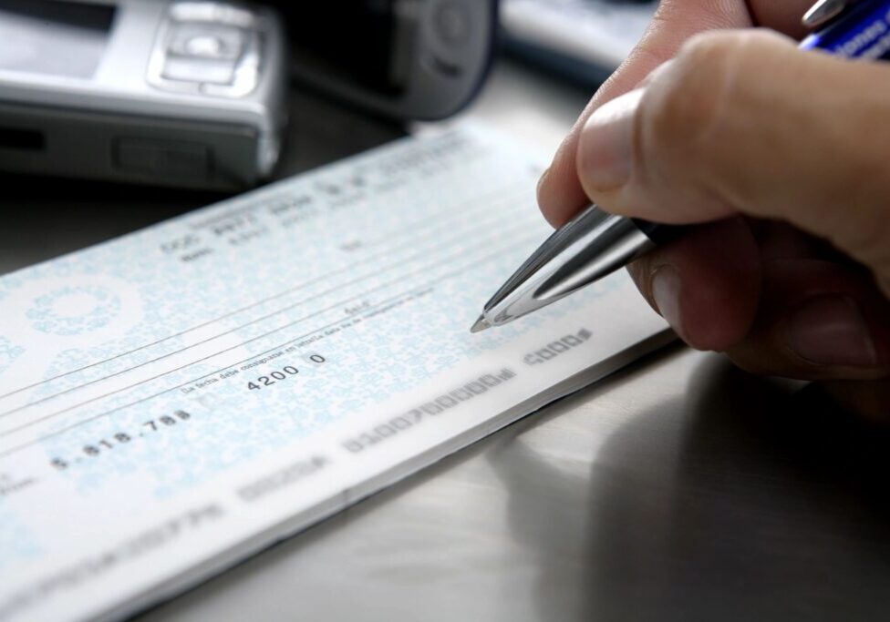 Person filling out a check with a pen.