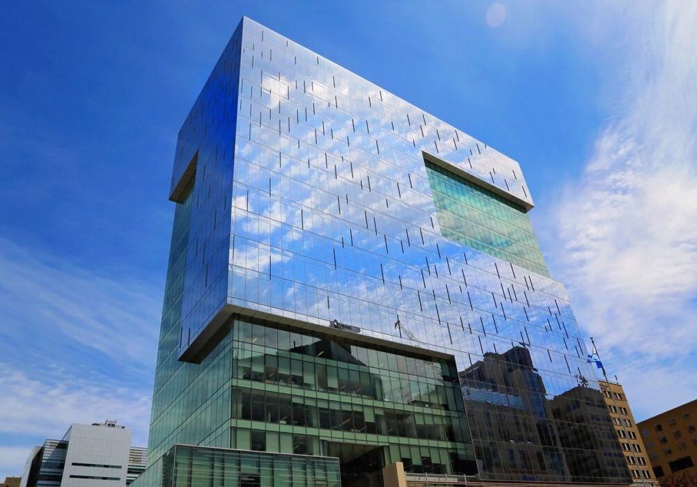 Modern glass building reflecting the blue sky and clouds.